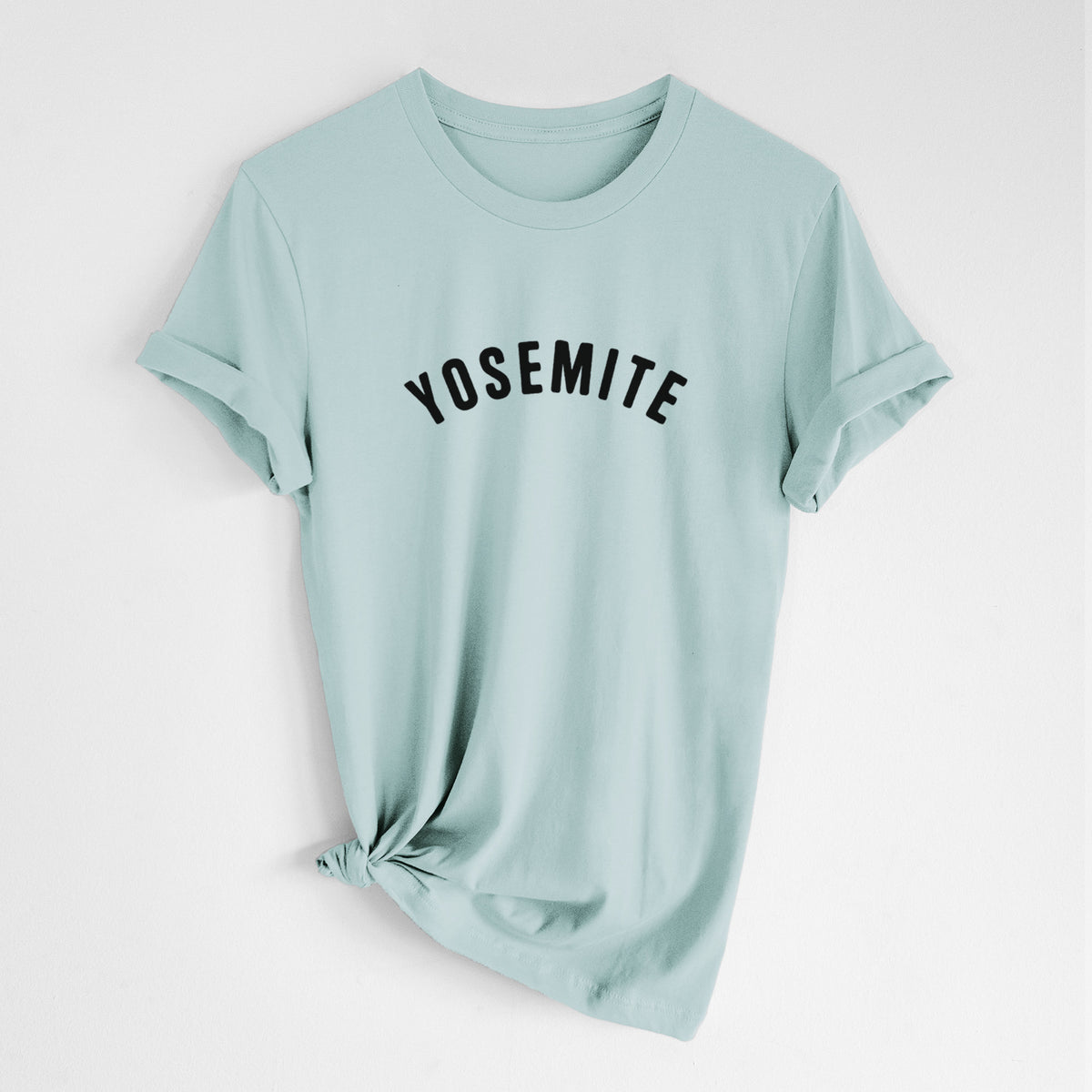 Dusty blue lightweight cotton t-shirt laid flat with the sleeves rolled, printed with the word Yosemite in bold black letters arched across the chest.