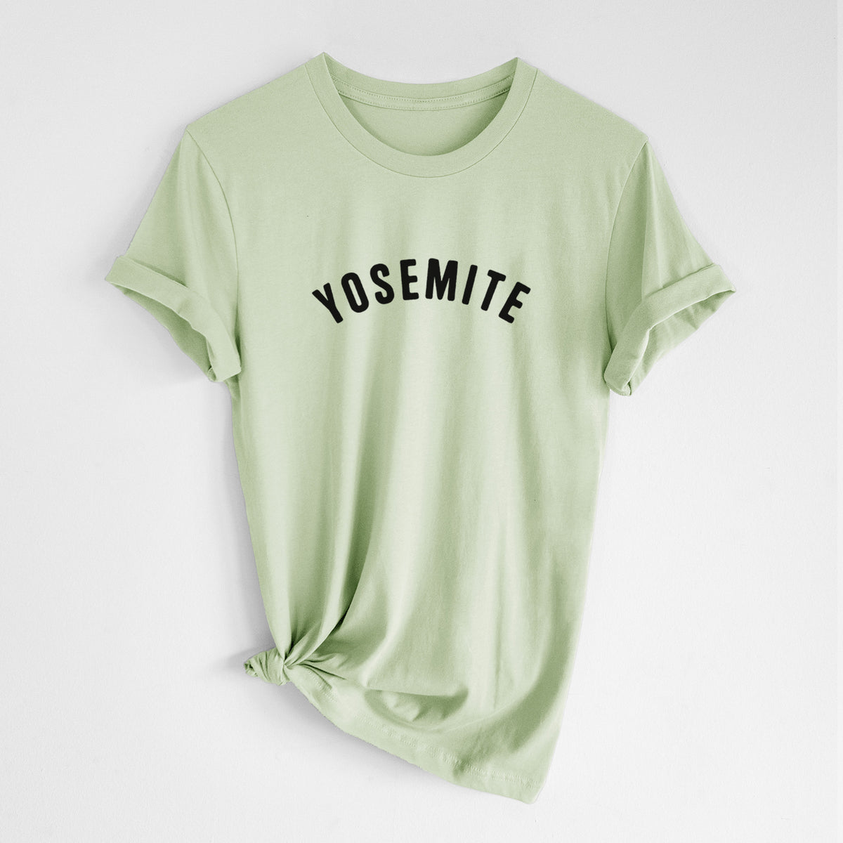 Spring green lightweight cotton t-shirt laid flat with the sleeves rolled, printed with the word Yosemite in bold black letters arched across the chest.