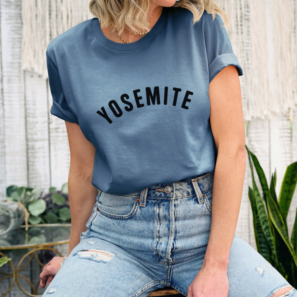 Woman wearing a steel blue lightweight cotton t-shirt printed with the word Yosemite in bold black letters arched across the chest.