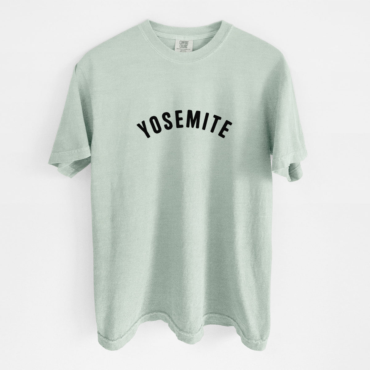 Bay green Comfort Colors t-shirt laid flat, printed with the word Yosemite in bold black letters arched across the chest.