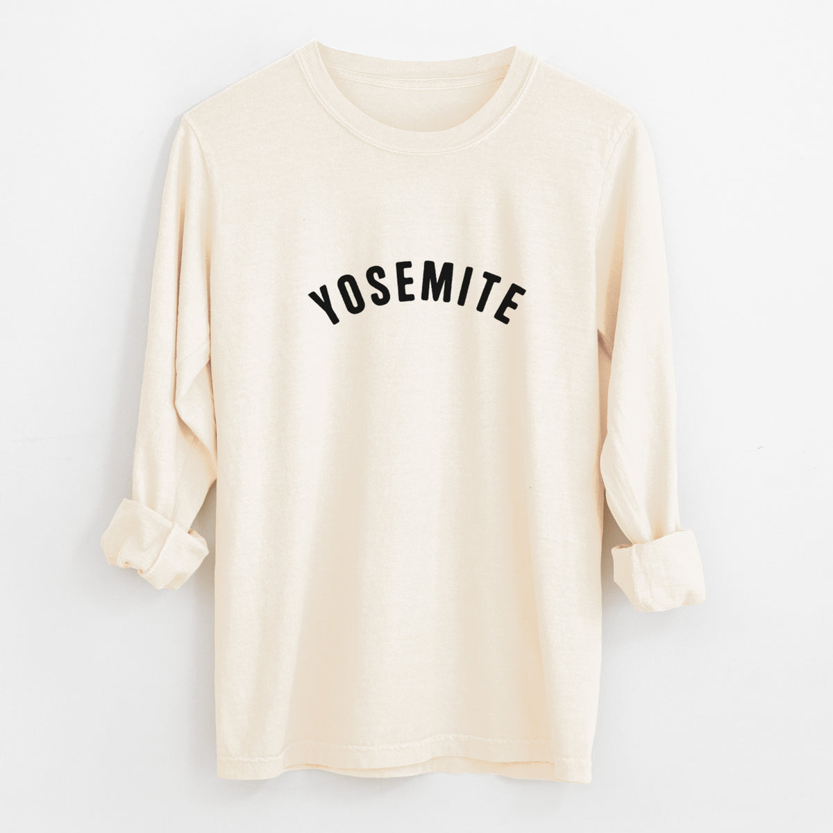 Ivory Comfort Colors long sleeve shirt laid flat with the cuffs rolled, printed with the word Yosemite in bold black letters arched across the chest.
