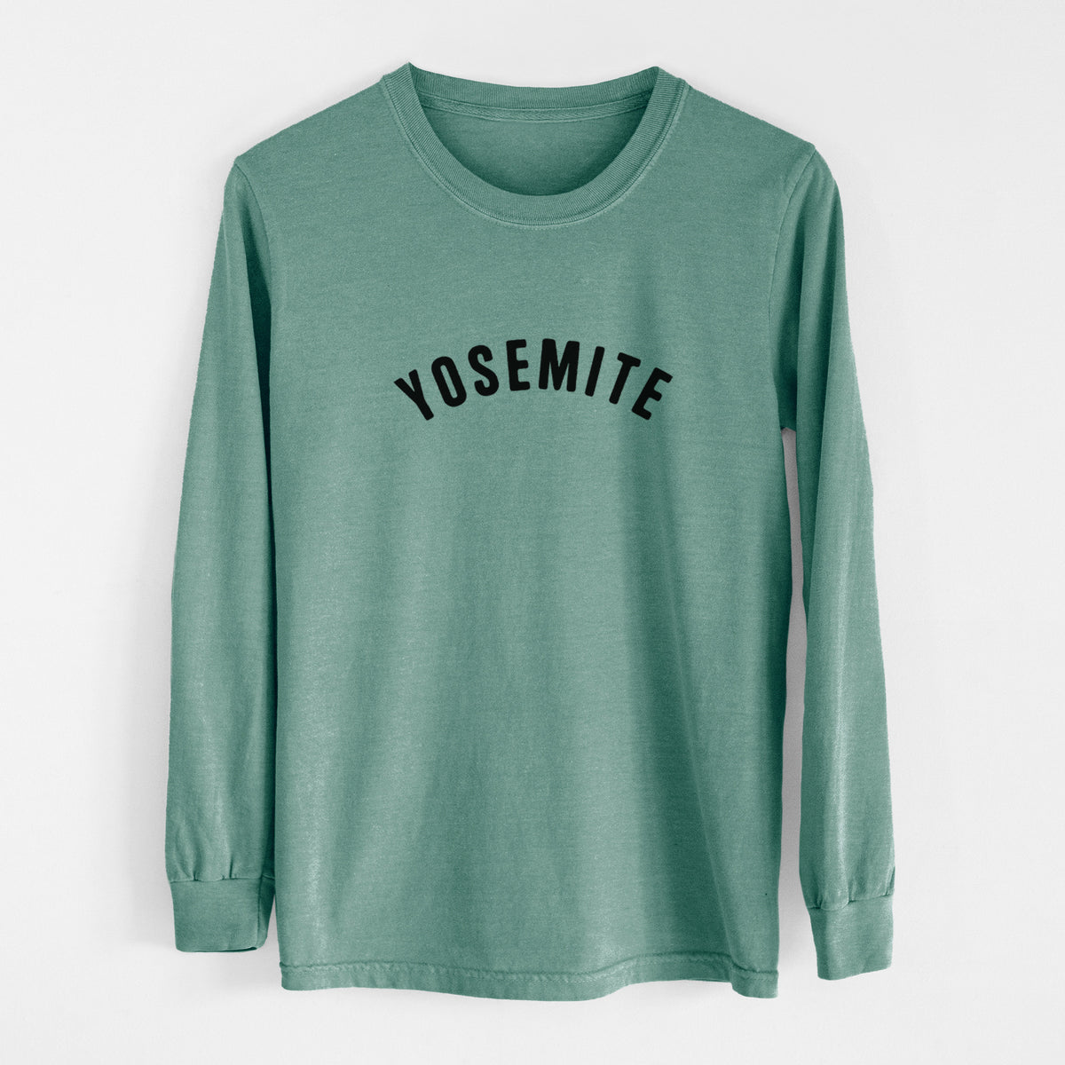 Pine green Comfort Colors long sleeve shirt laid flat, printed with the word Yosemite in bold black letters arched across the chest.