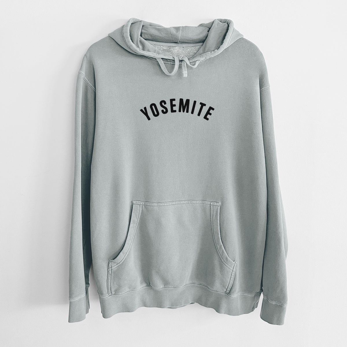 Sage green pigment dyed hoodie laid flat, printed with the word Yosemite in bold black letters arched across the chest.