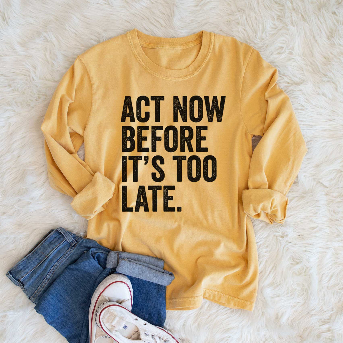 Golden wheat yellow Comfort Colors long sleeve shirt printed with bold black words reading Act Now Before It's Too Late, shown in a lifestyle photo.