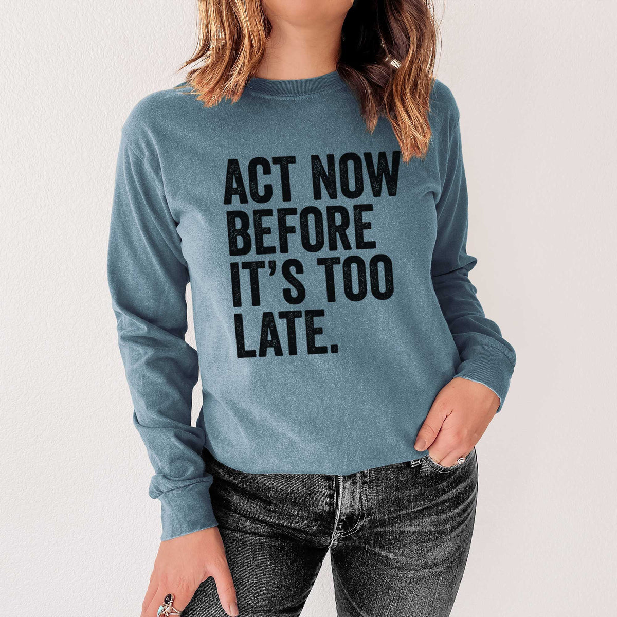 Steel blue Comfort Colors long sleeve shirt printed with bold black words reading Act Now Before It's Too Late, shown in a lifestyle photo.