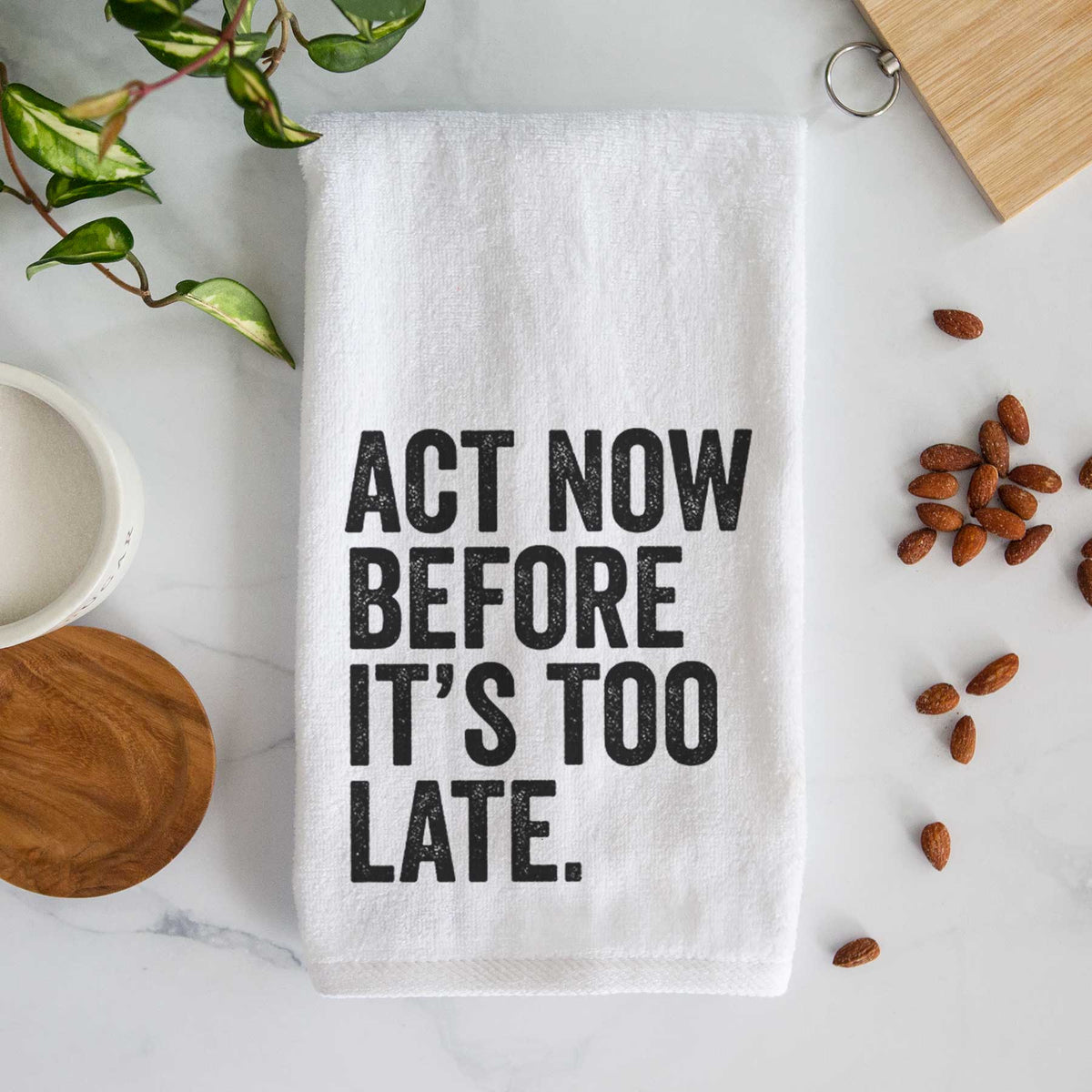 White hand towel printed with bold black words reading Act Now Before It's Too Late.