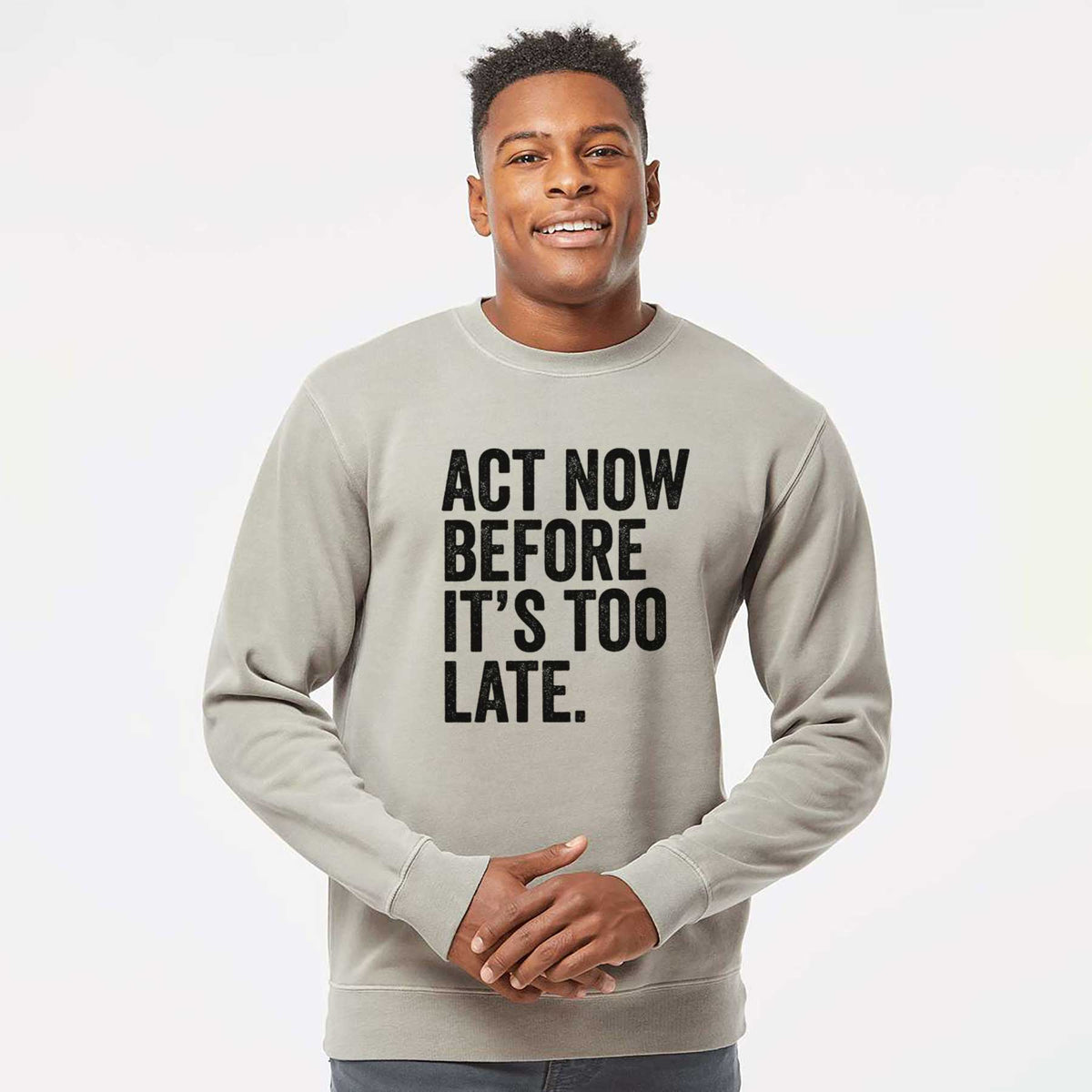 Model wearing a cement grey pigment dyed crewneck sweatshirt printed with bold black words reading Act Now Before It's Too Late.