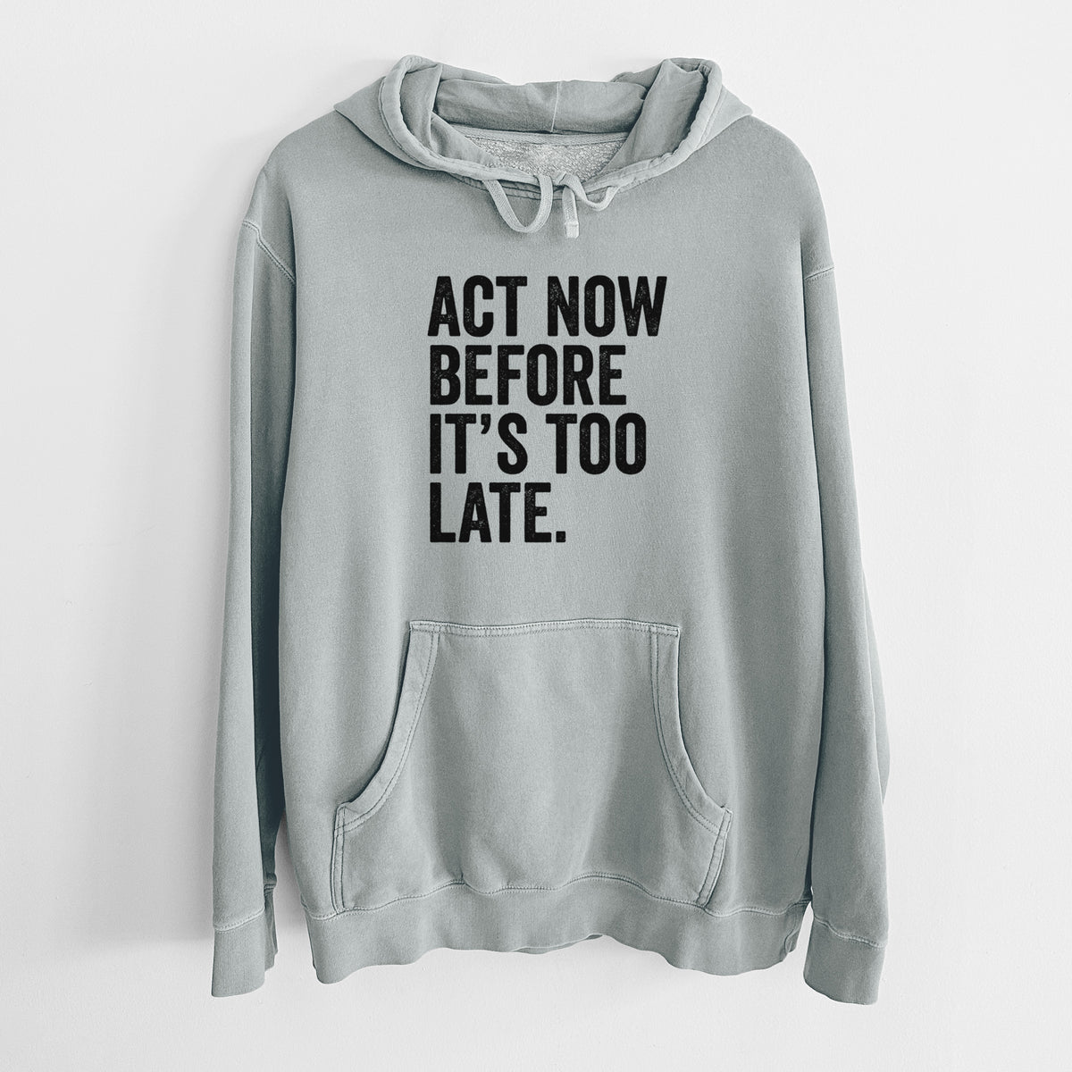 Sage green pigment dyed hoodie laid flat, printed with bold black words reading Act Now Before It's Too Late.