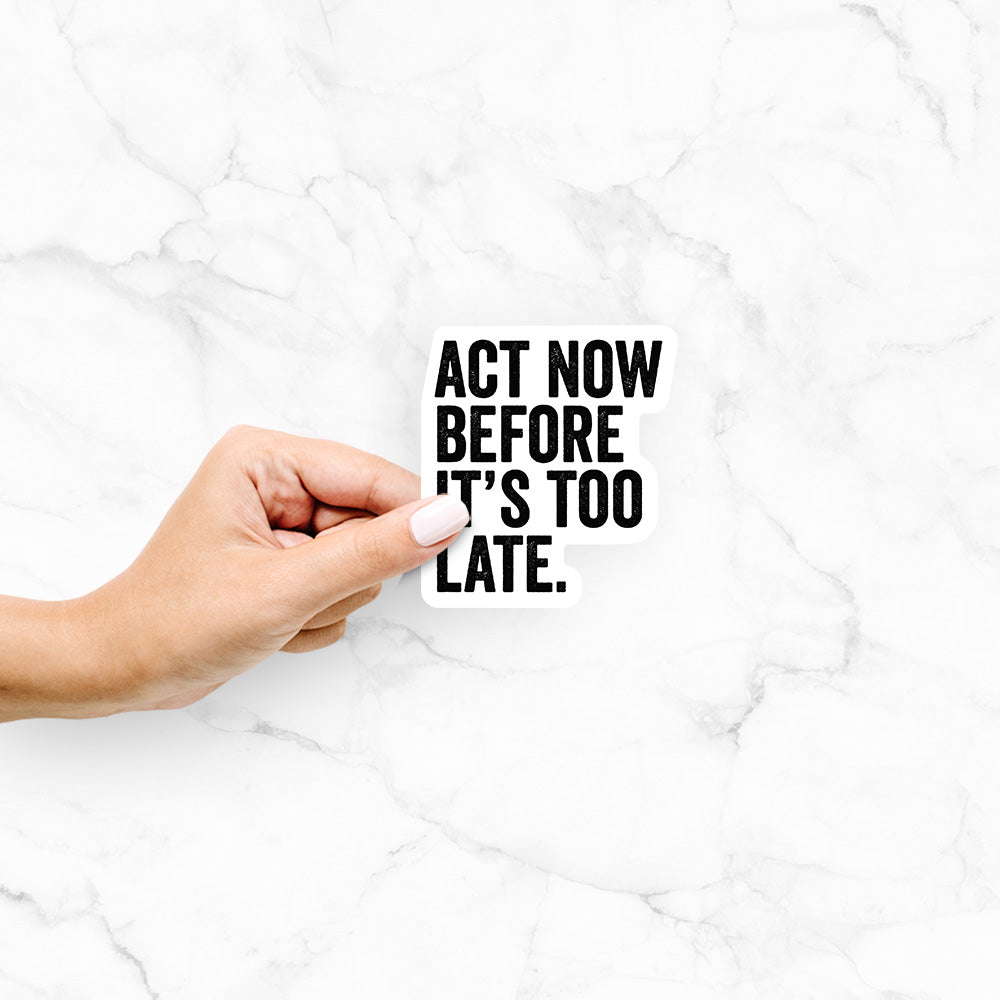 Hand holding a 4 inch vinyl decal of bold black words reading Act Now Before It's Too Late.
