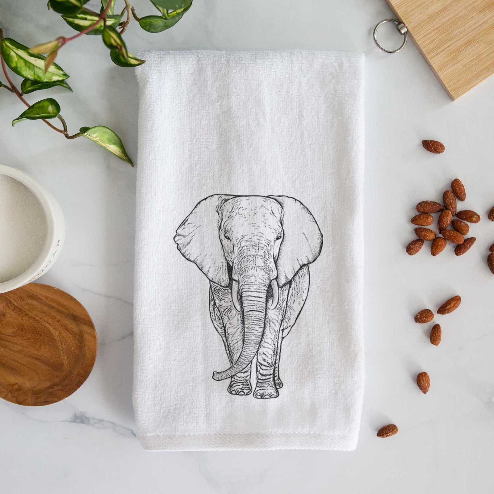 White hand towel printed with a black ink line drawing of an African elephant facing forward with large ears and tusks.