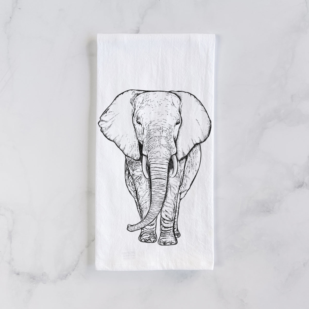 White cotton tea towel laid flat on marble, printed with a black ink line drawing of an African elephant facing forward with large ears and tusks.