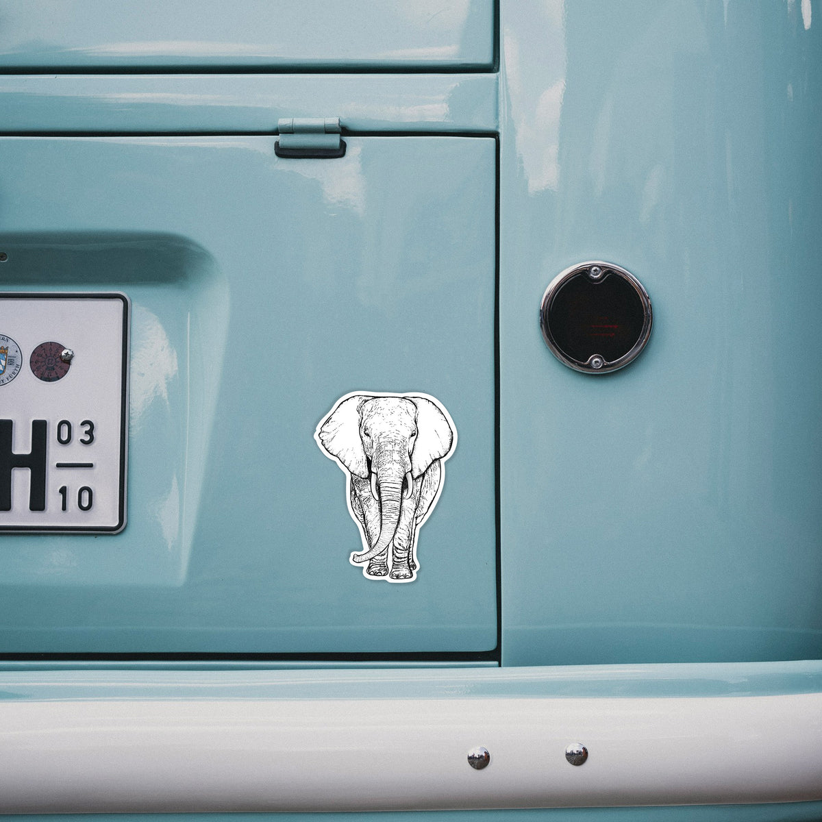 4 inch vinyl decal of a black ink line drawing of an African elephant facing forward with large ears and tusks on the back of a van.