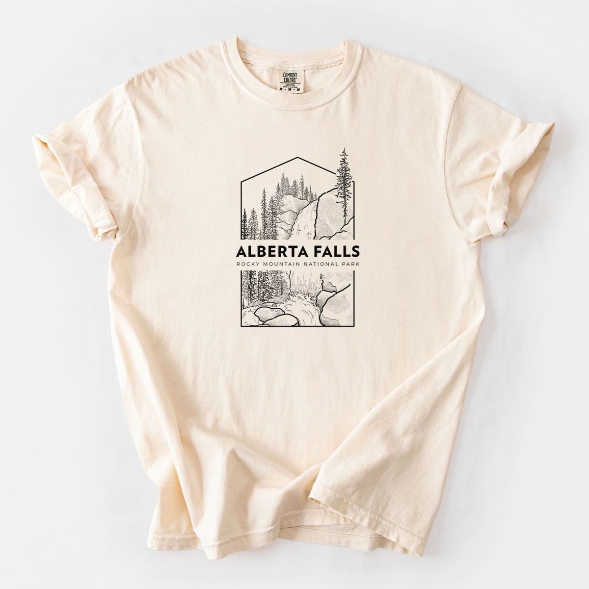 Ivory Comfort Colors t-shirt laid flat, printed with a black line art badge of Alberta Falls with pine trees, with the words Alberta Falls, Rocky Mountain National Park.