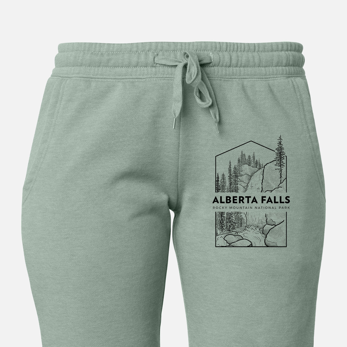 Front of sage green Cali Wave sweatpants, printed with a black line art badge of Alberta Falls with pine trees, with the words Alberta Falls, Rocky Mountain National Park on the leg.