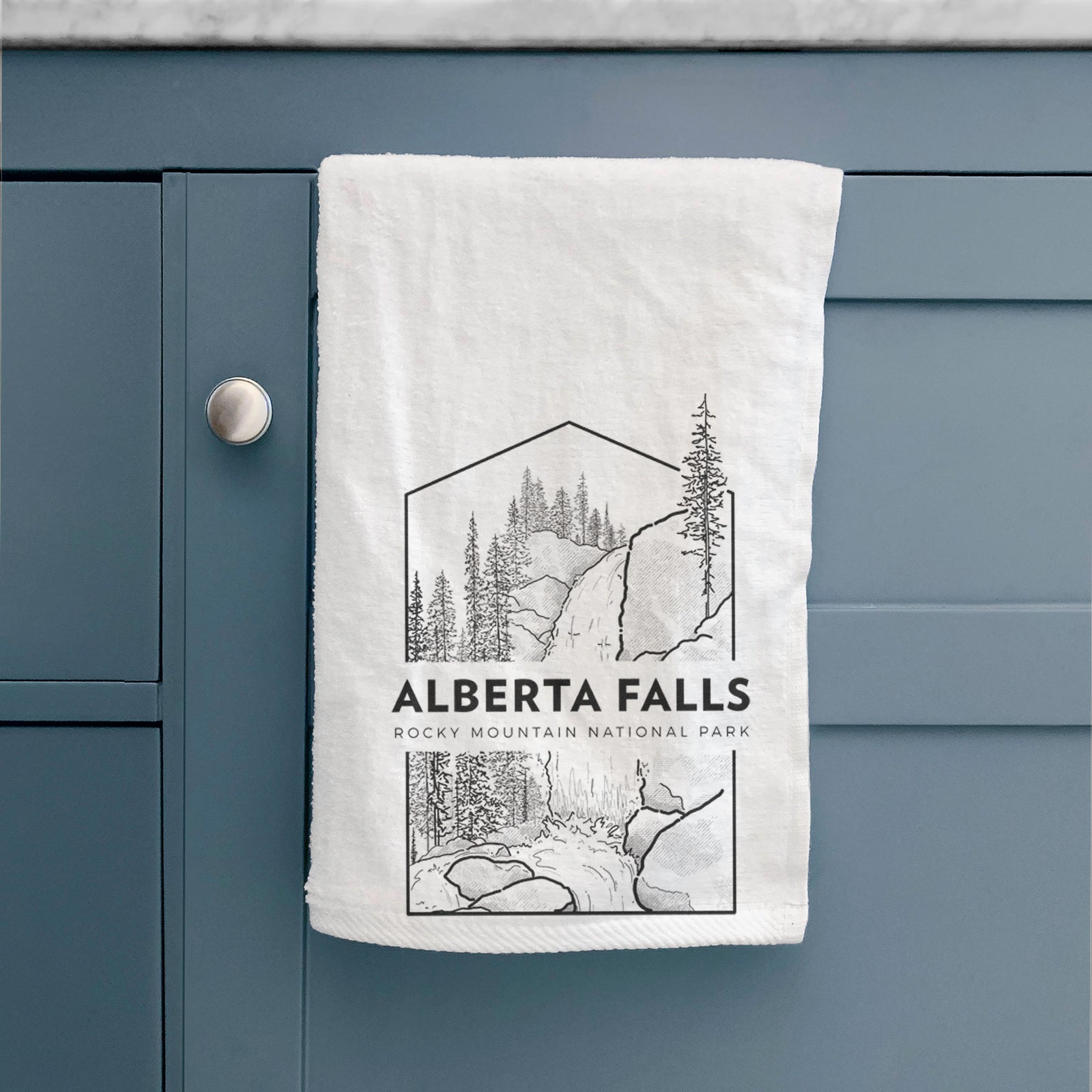 White hand towel printed with a black line art badge of Alberta Falls with pine trees, with the words Alberta Falls, Rocky Mountain National Park.