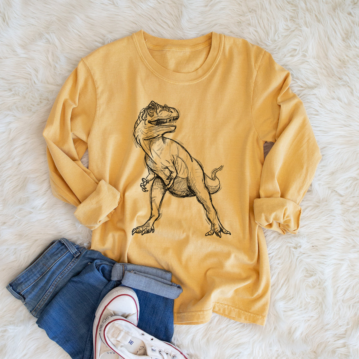 Golden wheat yellow Comfort Colors long sleeve shirt printed with a black ink illustration of an Allosaurus walking, shown in a lifestyle photo.