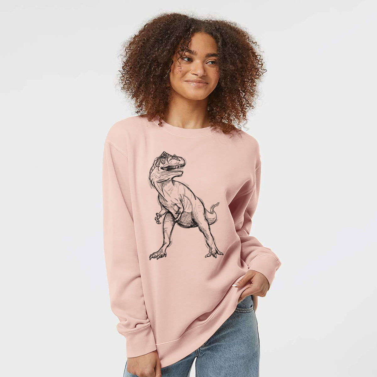 Model wearing a dusty pink pigment dyed crewneck sweatshirt printed with a black ink illustration of an Allosaurus walking.