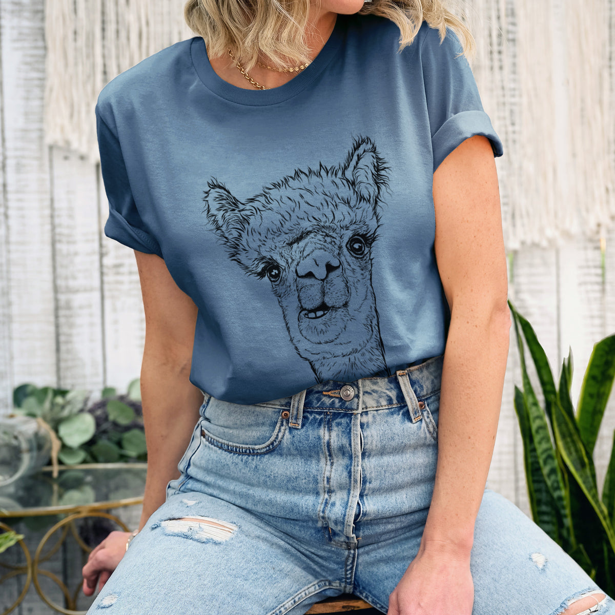Woman wearing a steel blue lightweight cotton t-shirt printed with a detailed black ink portrait of a fluffy alpaca's head and neck.