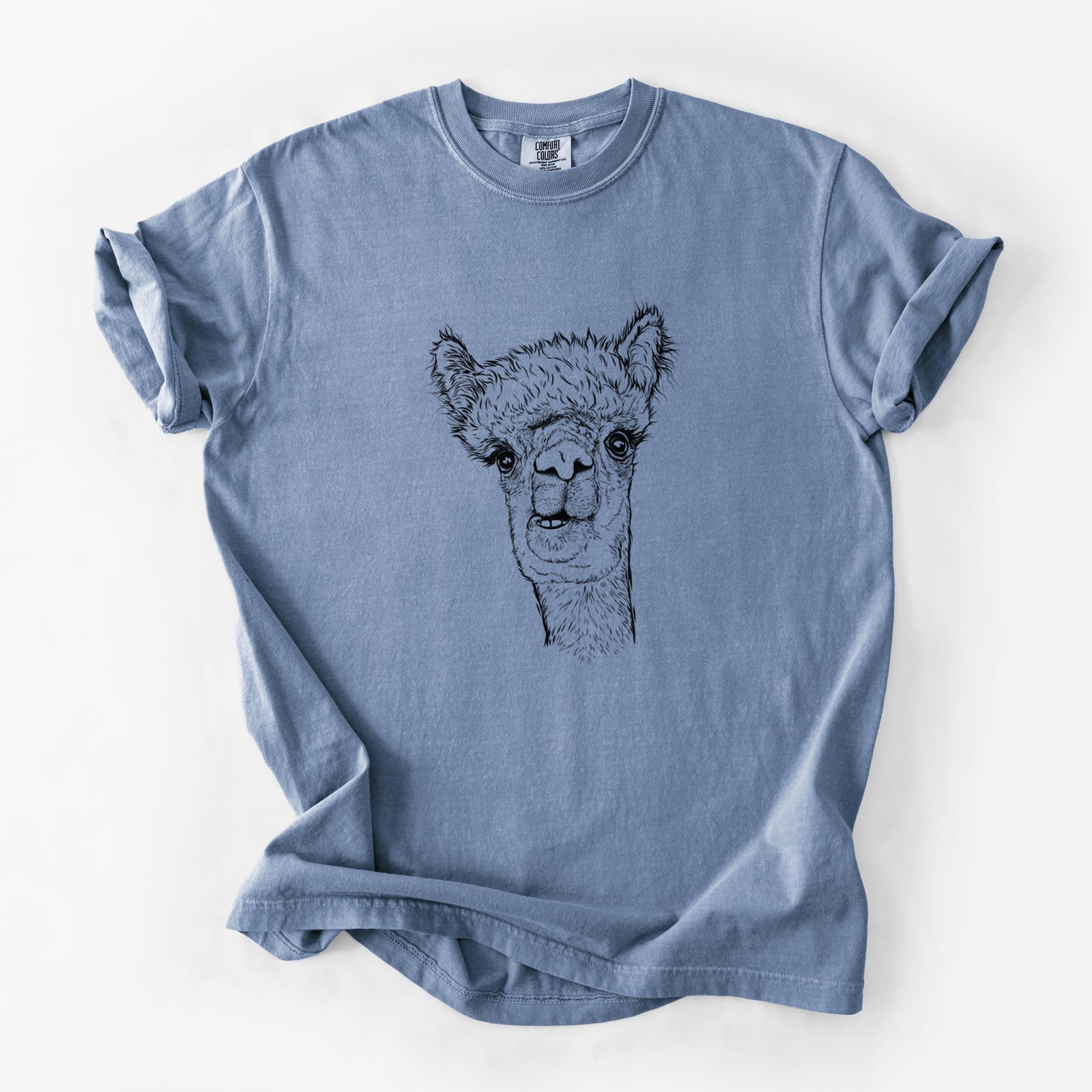 Blue jean Comfort Colors t-shirt laid flat, printed with a detailed black ink portrait of a fluffy alpaca's head and neck.
