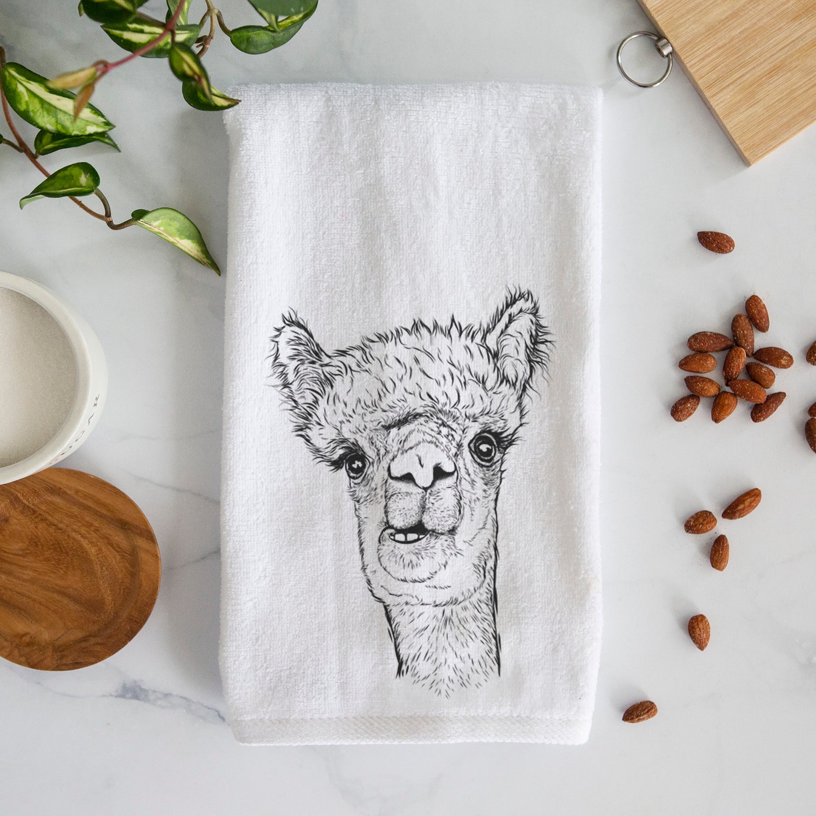 White hand towel printed with a detailed black ink portrait of a fluffy alpaca's head and neck.