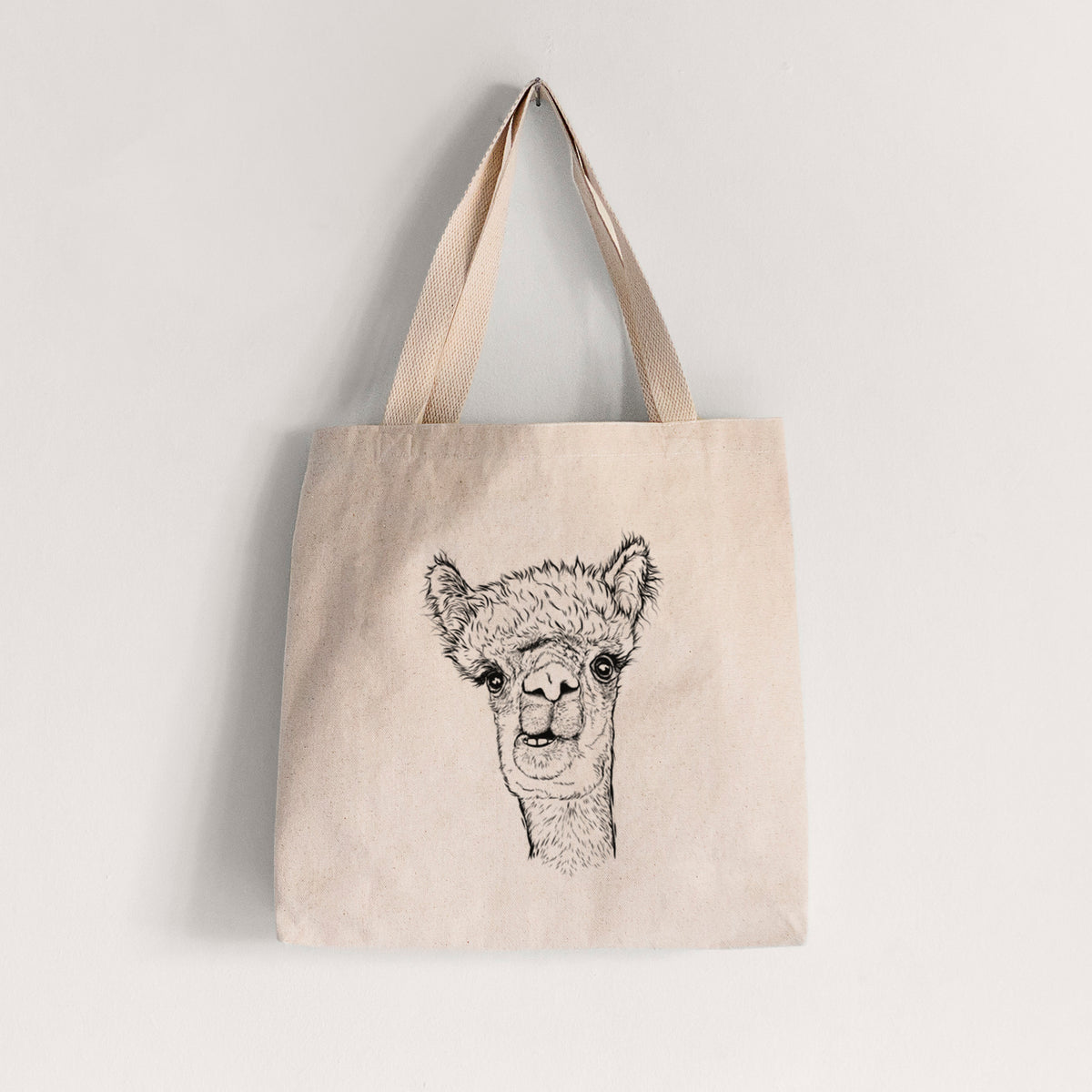 Natural canvas tote bag printed with a detailed black ink portrait of a fluffy alpaca's head and neck.