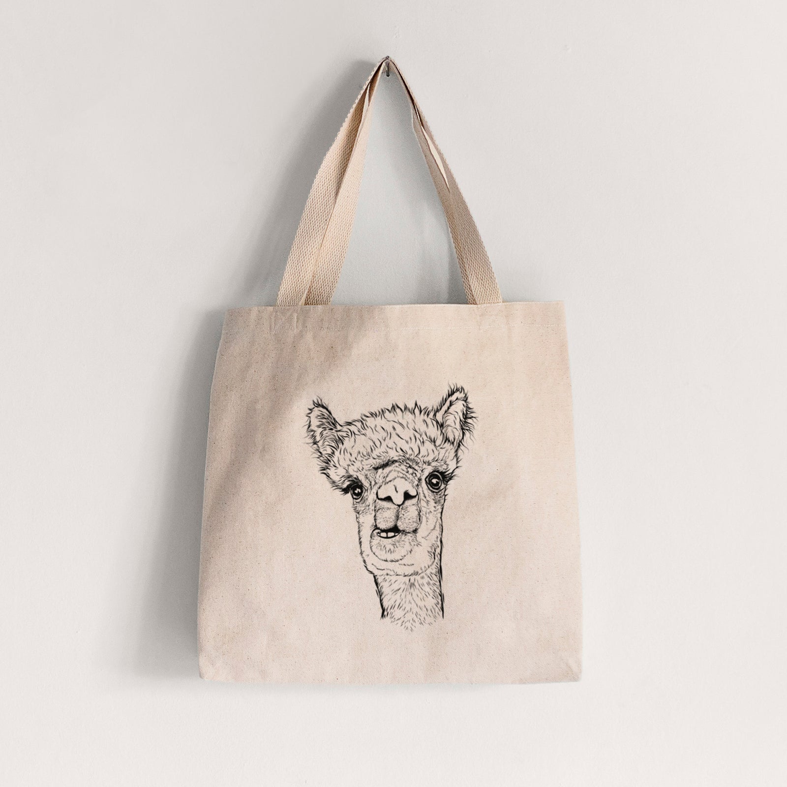 Natural canvas tote bag printed with a detailed black ink portrait of a fluffy alpaca's head and neck.