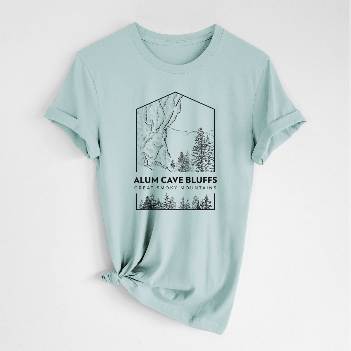 Dusty blue lightweight cotton t-shirt laid flat with the sleeves rolled, printed with a black line art badge of Alum Cave Bluffs with pine trees, with the words Alum Cave Bluffs, Great Smoky Mountains.