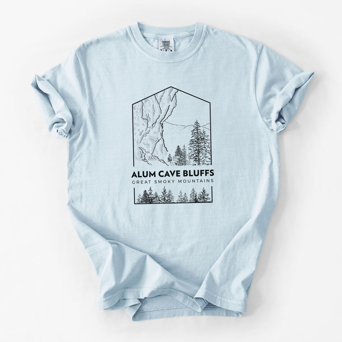 Chambray blue Comfort Colors t-shirt laid flat, printed with a black line art badge of Alum Cave Bluffs with pine trees, with the words Alum Cave Bluffs, Great Smoky Mountains.