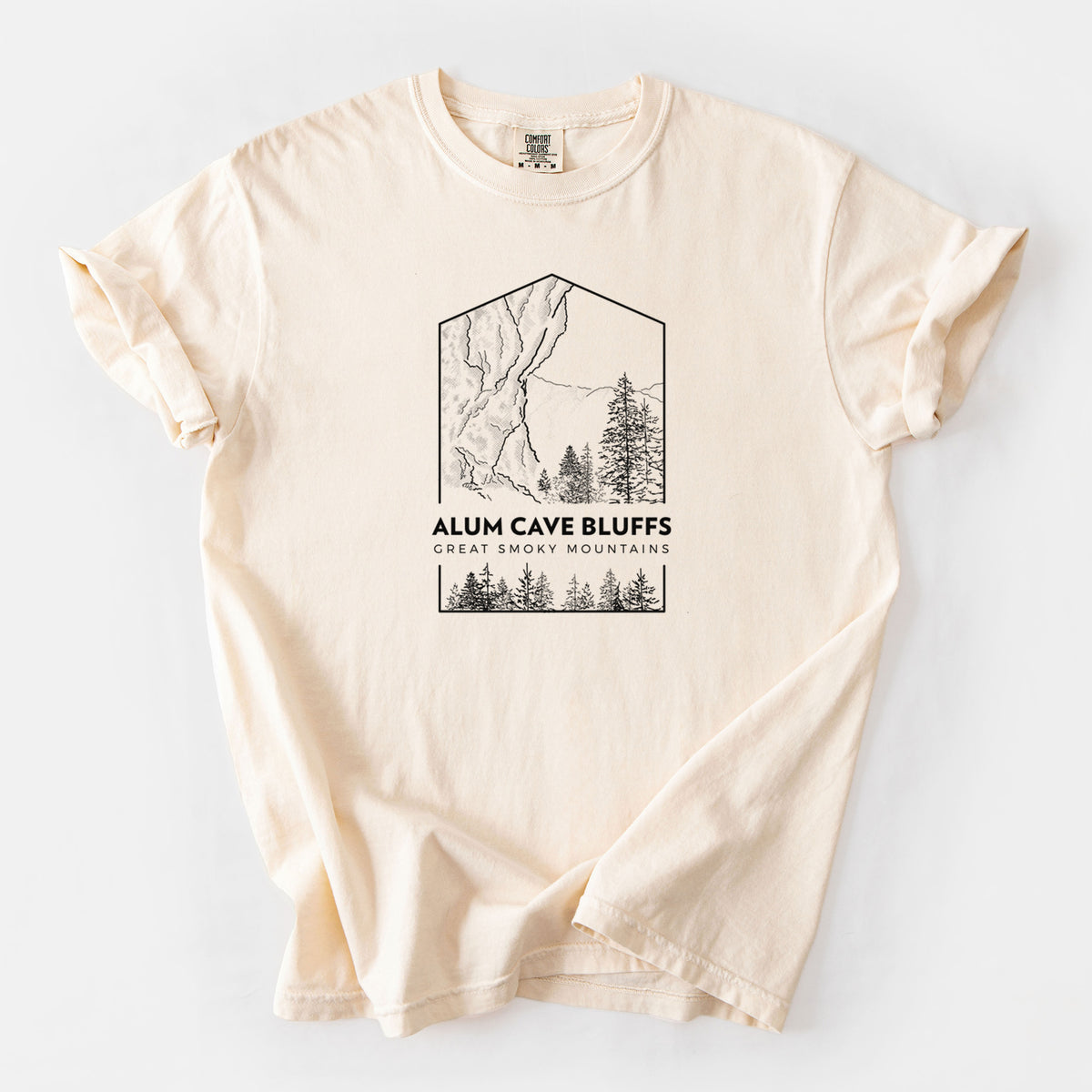 Ivory Comfort Colors t-shirt laid flat, printed with a black line art badge of Alum Cave Bluffs with pine trees, with the words Alum Cave Bluffs, Great Smoky Mountains.