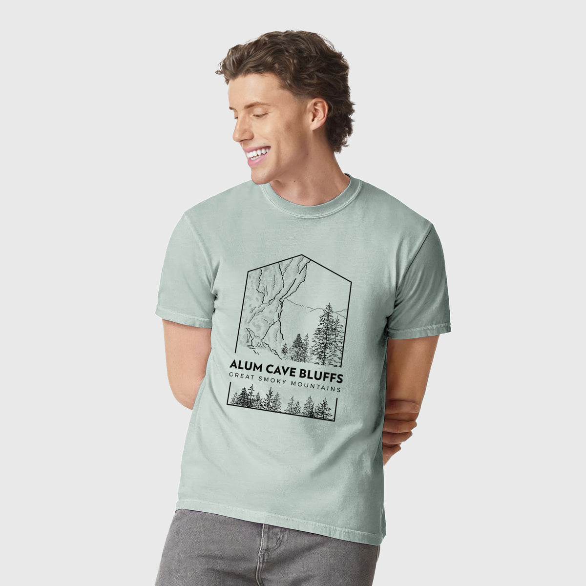 Man wearing a Comfort Colors t-shirt printed with a black line art badge of Alum Cave Bluffs with pine trees, with the words Alum Cave Bluffs, Great Smoky Mountains.