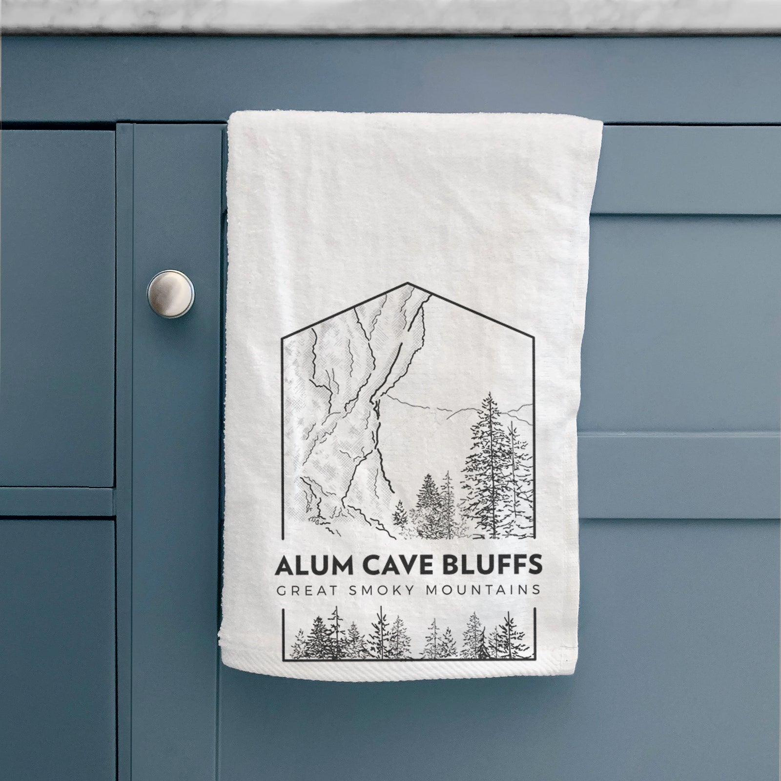 White hand towel printed with a black line art badge of Alum Cave Bluffs with pine trees, with the words Alum Cave Bluffs, Great Smoky Mountains.