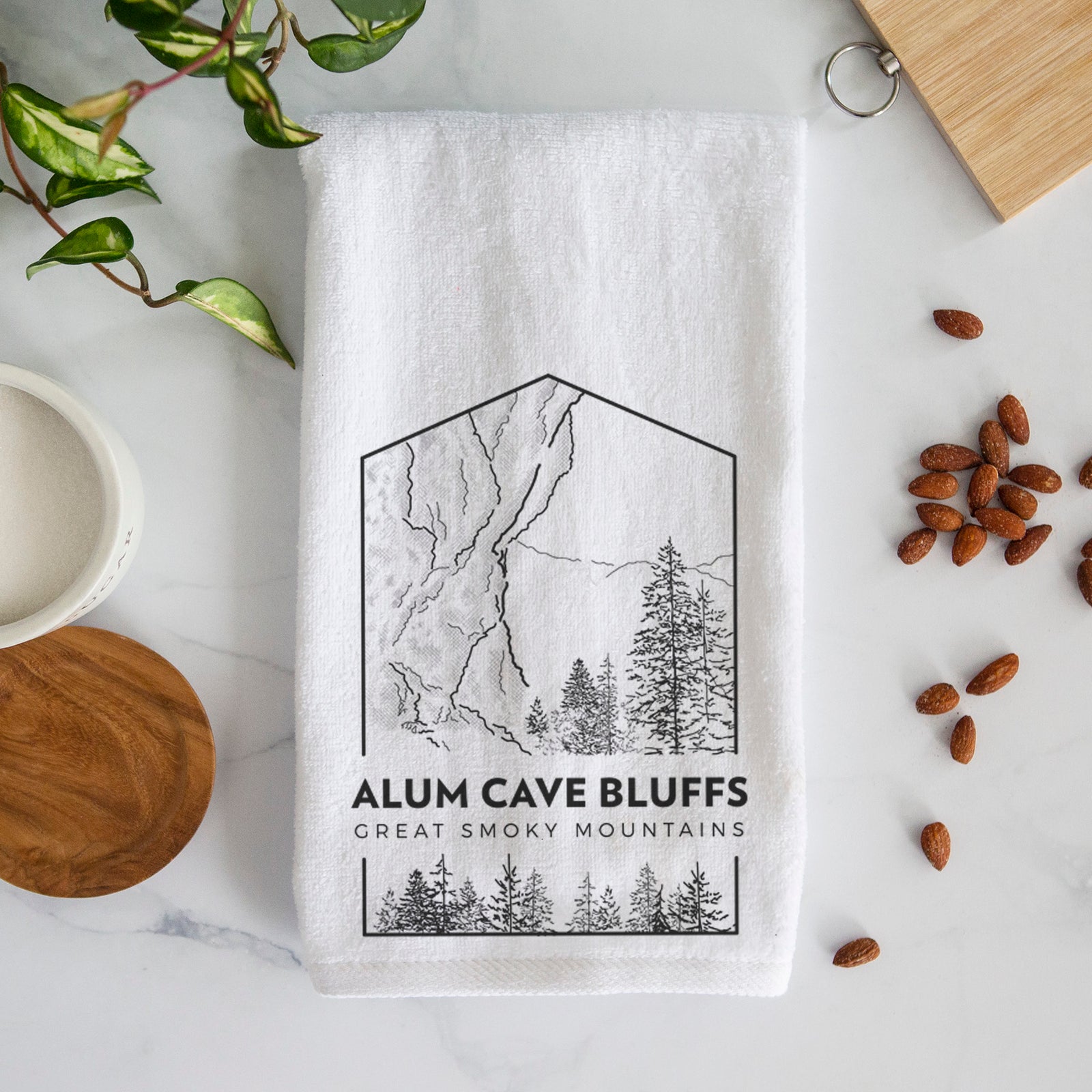 White hand towel printed with a black line art badge of Alum Cave Bluffs with pine trees, with the words Alum Cave Bluffs, Great Smoky Mountains.