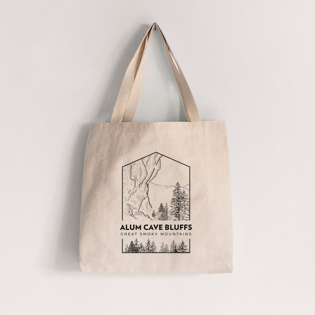 Natural canvas tote bag printed with a black line art badge of Alum Cave Bluffs with pine trees, with the words Alum Cave Bluffs, Great Smoky Mountains.