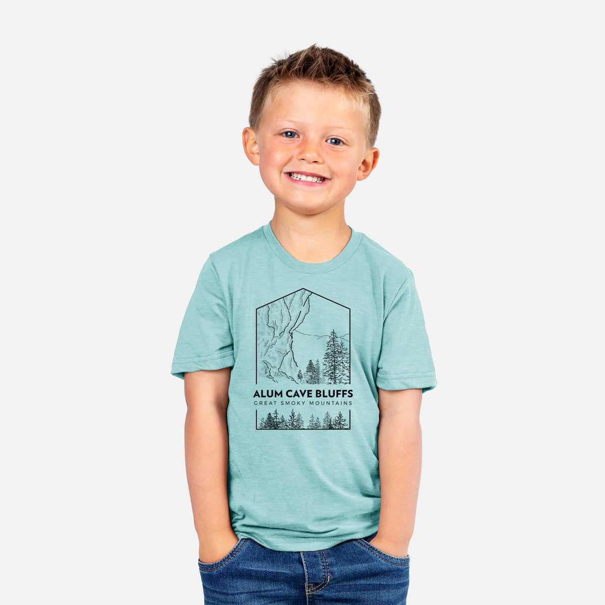 Smiling boy wearing a youth t-shirt printed with a black line art badge of Alum Cave Bluffs with pine trees, with the words Alum Cave Bluffs, Great Smoky Mountains.