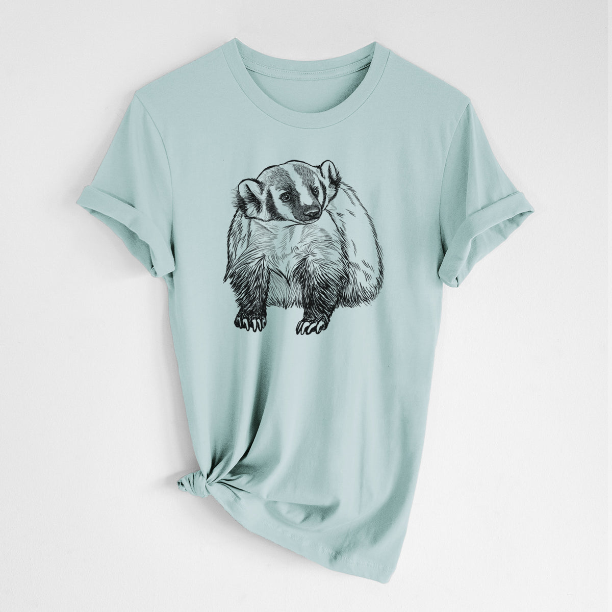 Dusty blue lightweight cotton t-shirt laid flat with the sleeves rolled, printed with a detailed black ink illustration of an American badger facing forward.