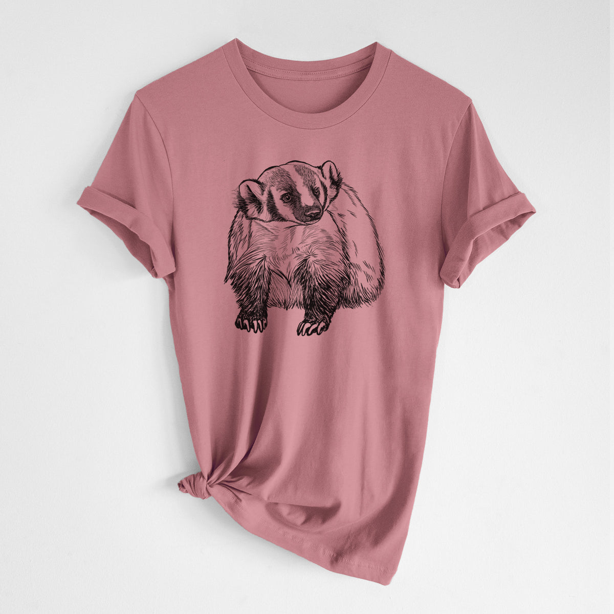 Mauve pink lightweight cotton t-shirt laid flat with the sleeves rolled, printed with a detailed black ink illustration of an American badger facing forward.