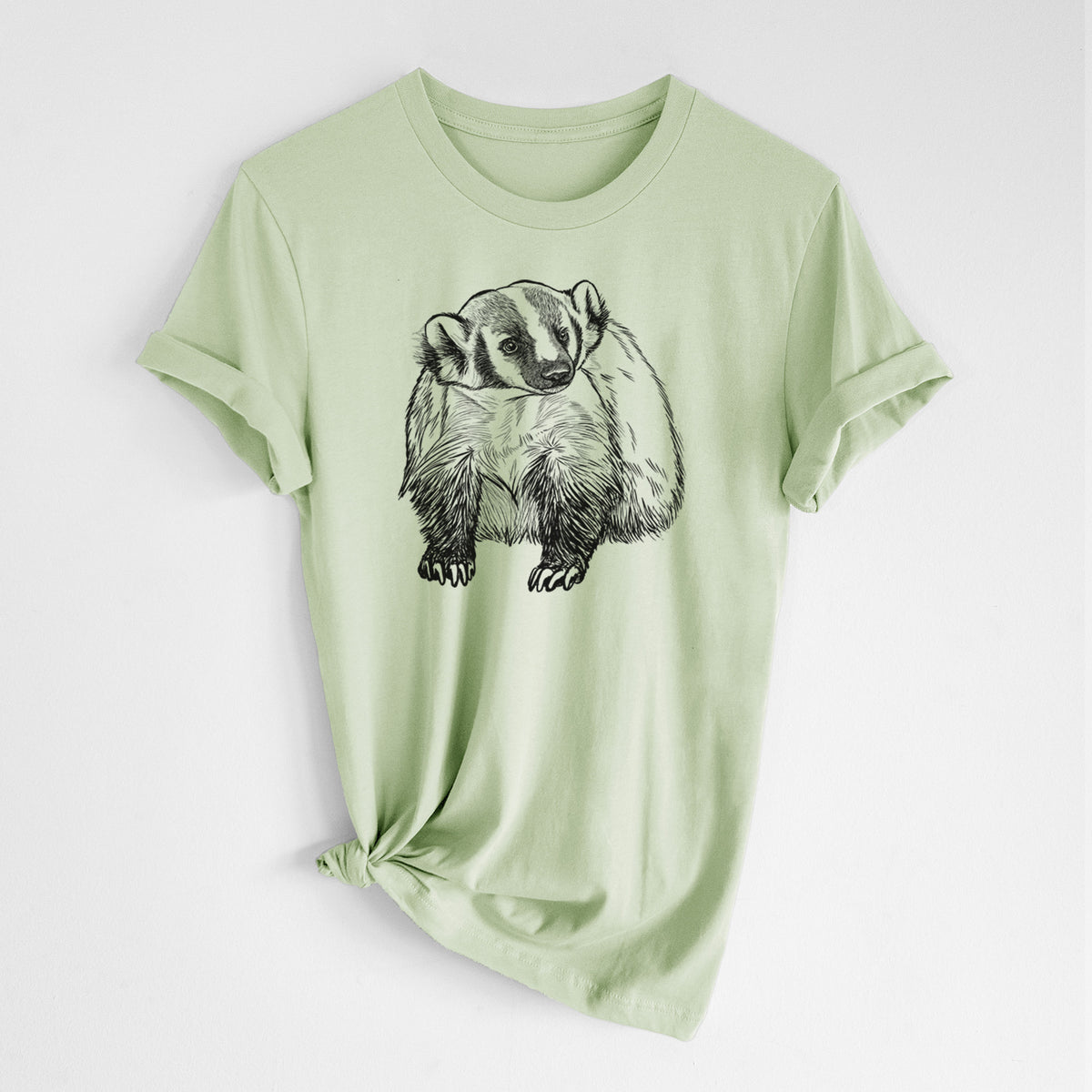 Spring green lightweight cotton t-shirt laid flat with the sleeves rolled, printed with a detailed black ink illustration of an American badger facing forward.