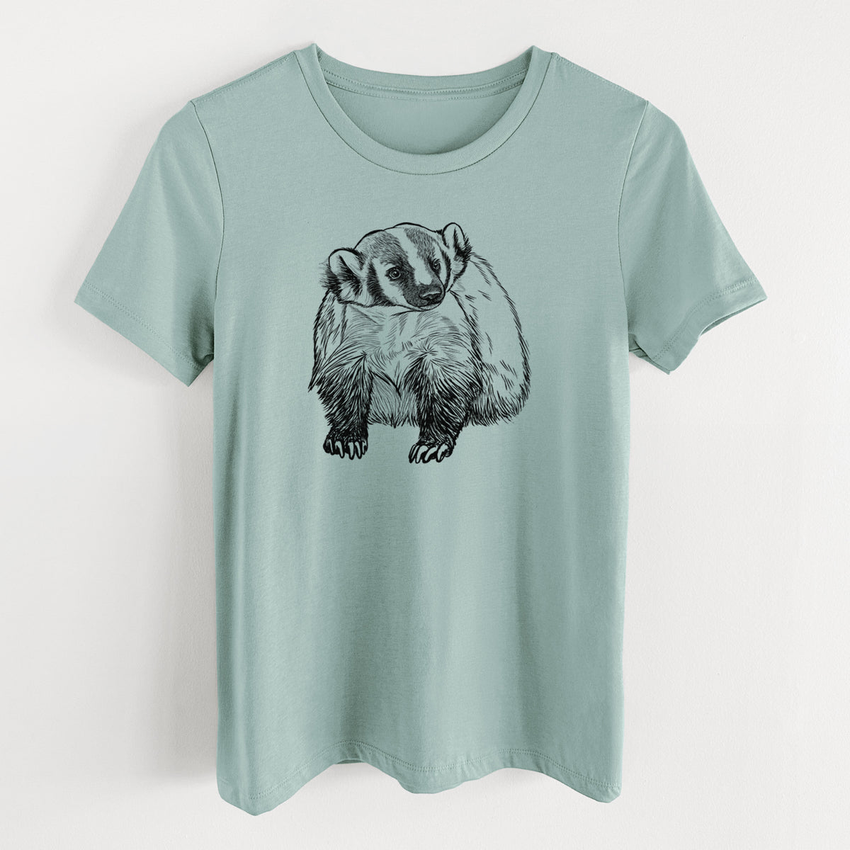 Dusty blue women's relaxed fit cotton t-shirt laid flat, printed with a detailed black ink illustration of an American badger facing forward.