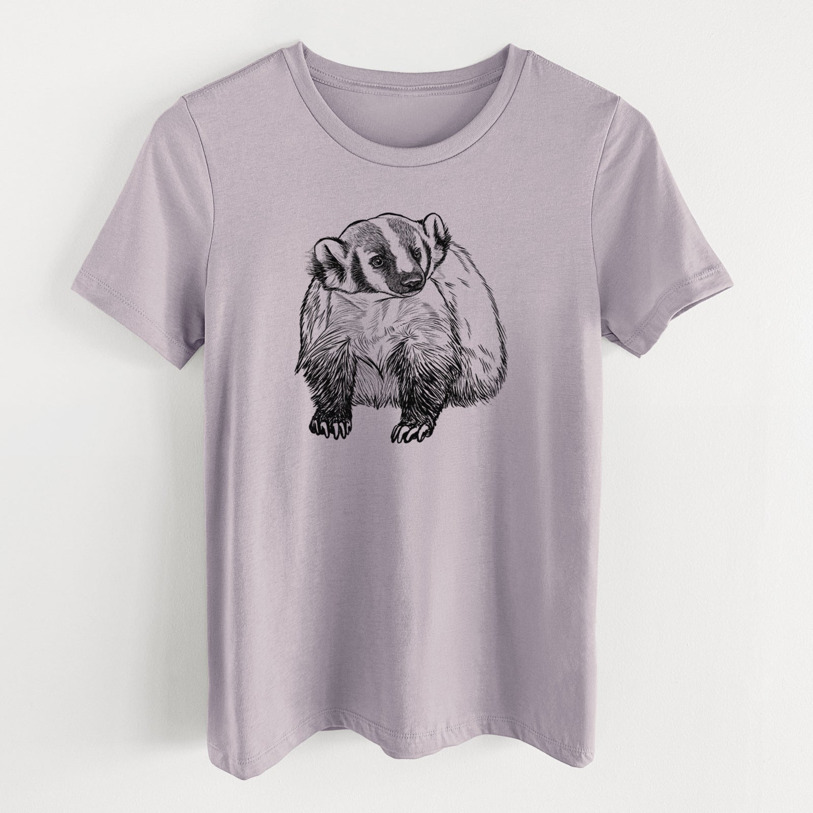 Light violet women's relaxed fit cotton t-shirt laid flat, printed with a detailed black ink illustration of an American badger facing forward.