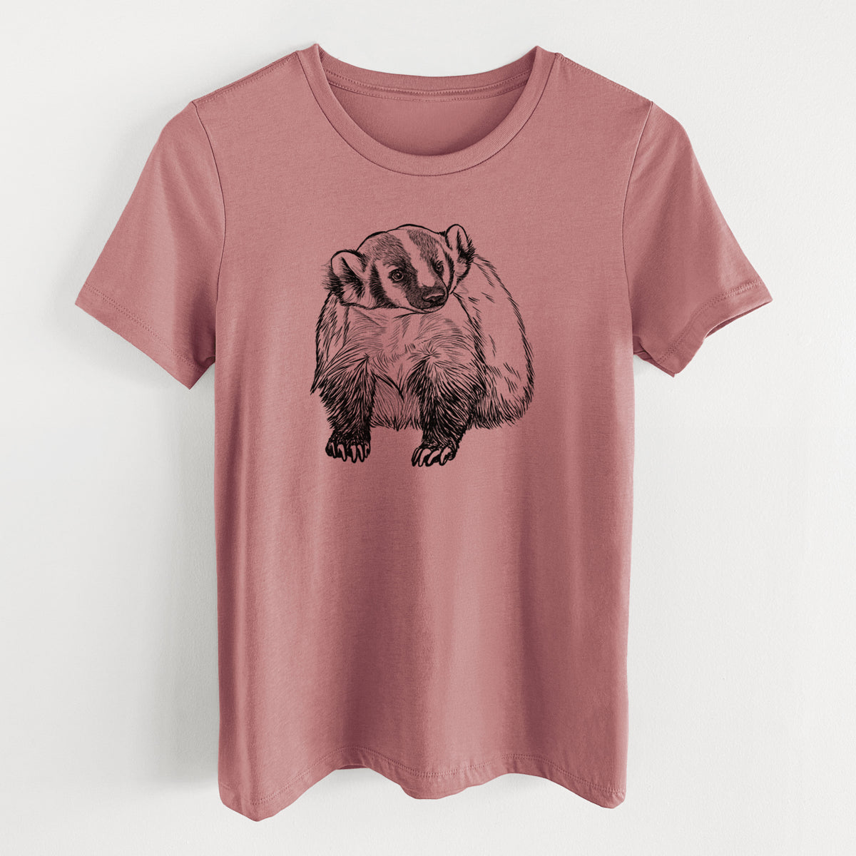 Mauve pink women's relaxed fit cotton t-shirt laid flat, printed with a detailed black ink illustration of an American badger facing forward.