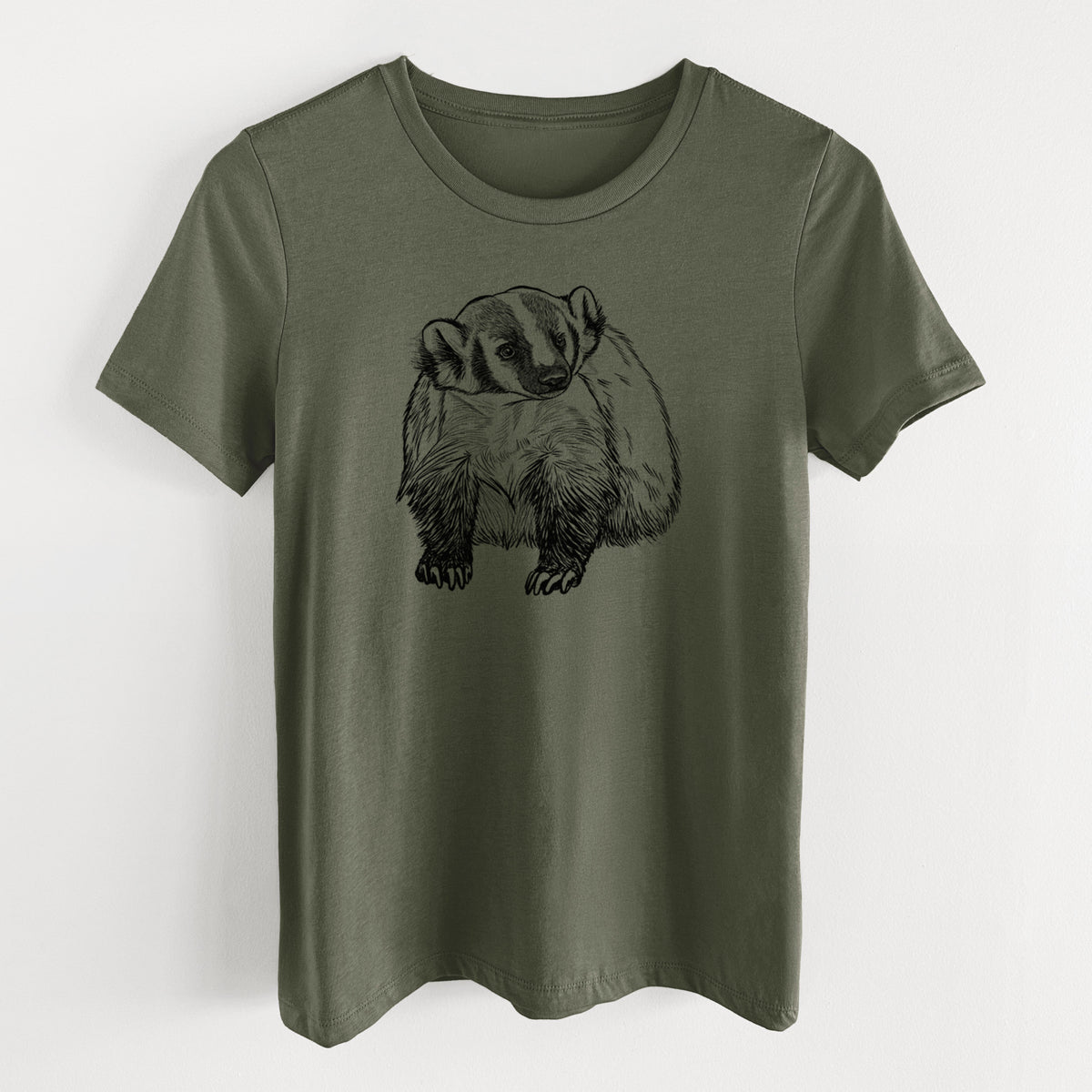 Military green women's relaxed fit cotton t-shirt laid flat, printed with a detailed black ink illustration of an American badger facing forward.