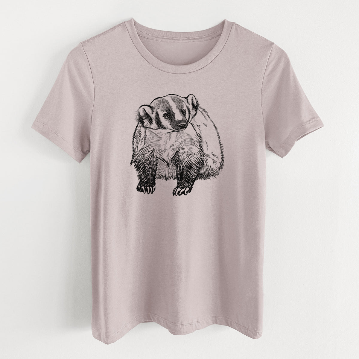 Pink gravel women's relaxed fit cotton t-shirt laid flat, printed with a detailed black ink illustration of an American badger facing forward.
