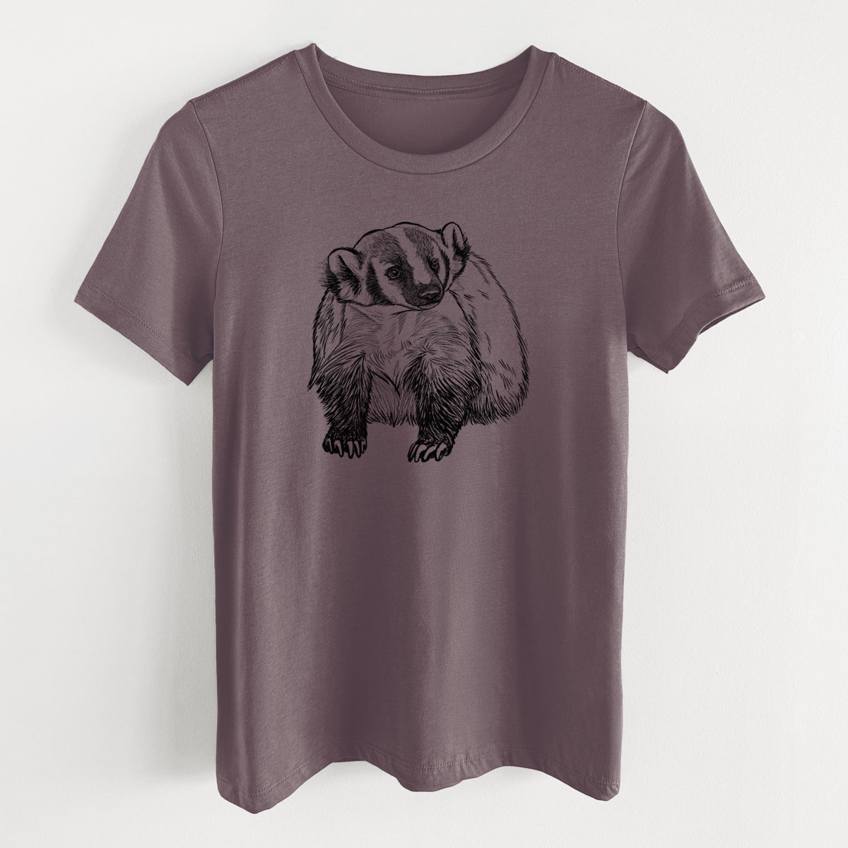 Purple storm women's relaxed fit cotton t-shirt laid flat, printed with a detailed black ink illustration of an American badger facing forward.