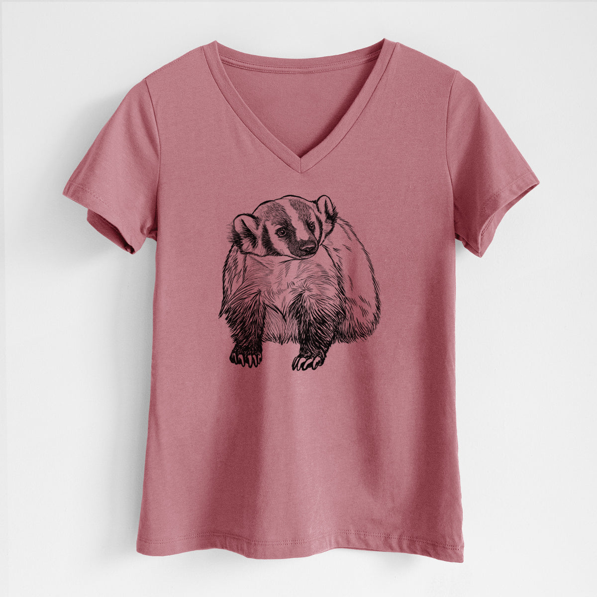 Mauve pink women's relaxed fit cotton V-neck t-shirt laid flat, printed with a detailed black ink illustration of an American badger facing forward.