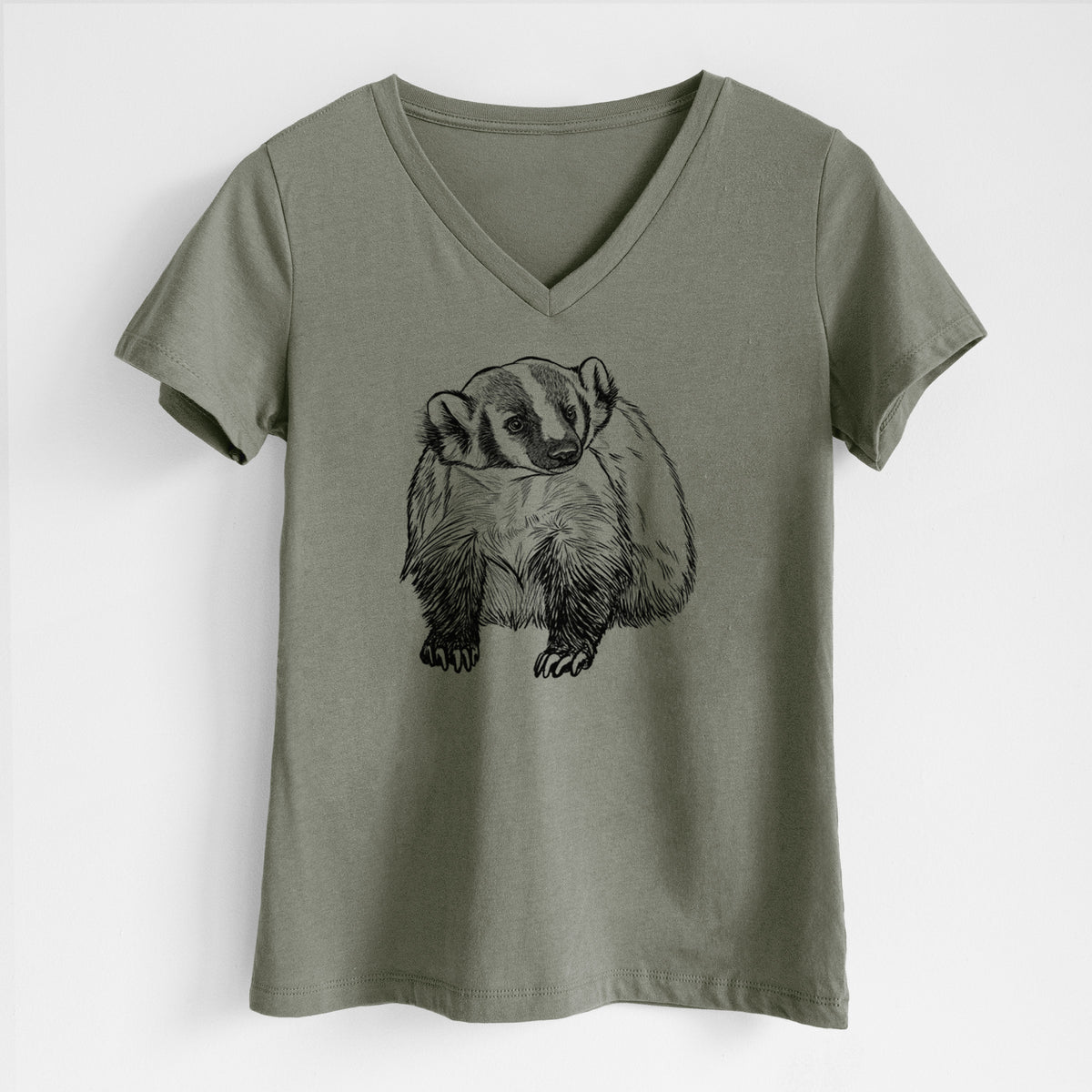 Military green women's relaxed fit cotton V-neck t-shirt laid flat, printed with a detailed black ink illustration of an American badger facing forward.