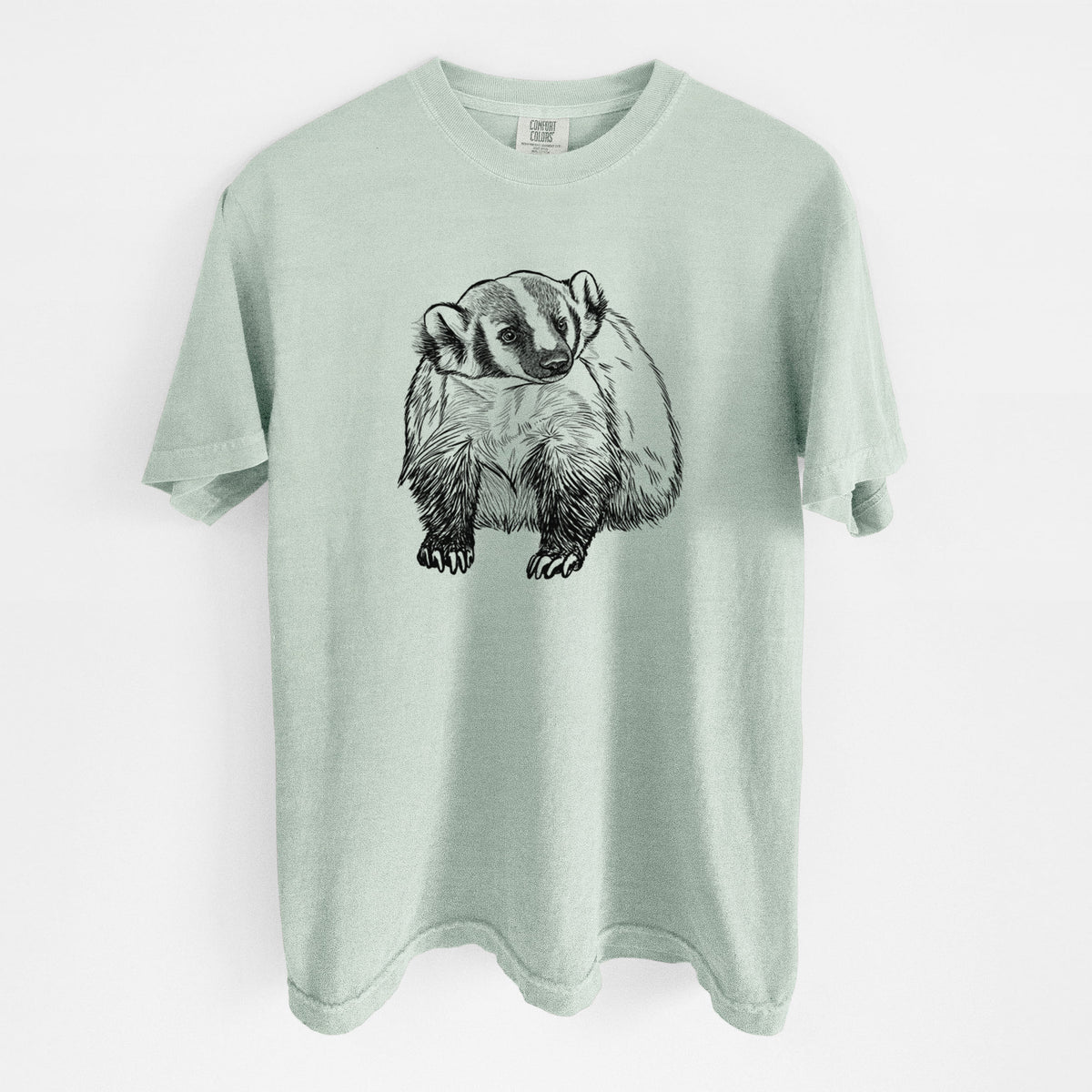 Bay green Comfort Colors t-shirt laid flat, printed with a detailed black ink illustration of an American badger facing forward.