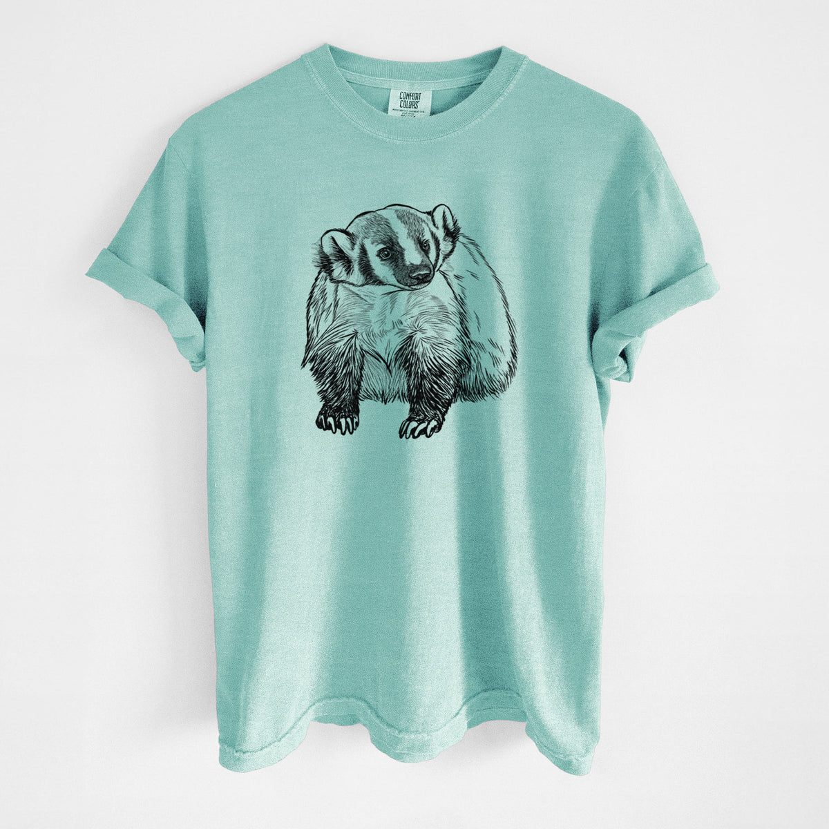 Chalky mint Comfort Colors t-shirt laid flat, printed with a detailed black ink illustration of an American badger facing forward.