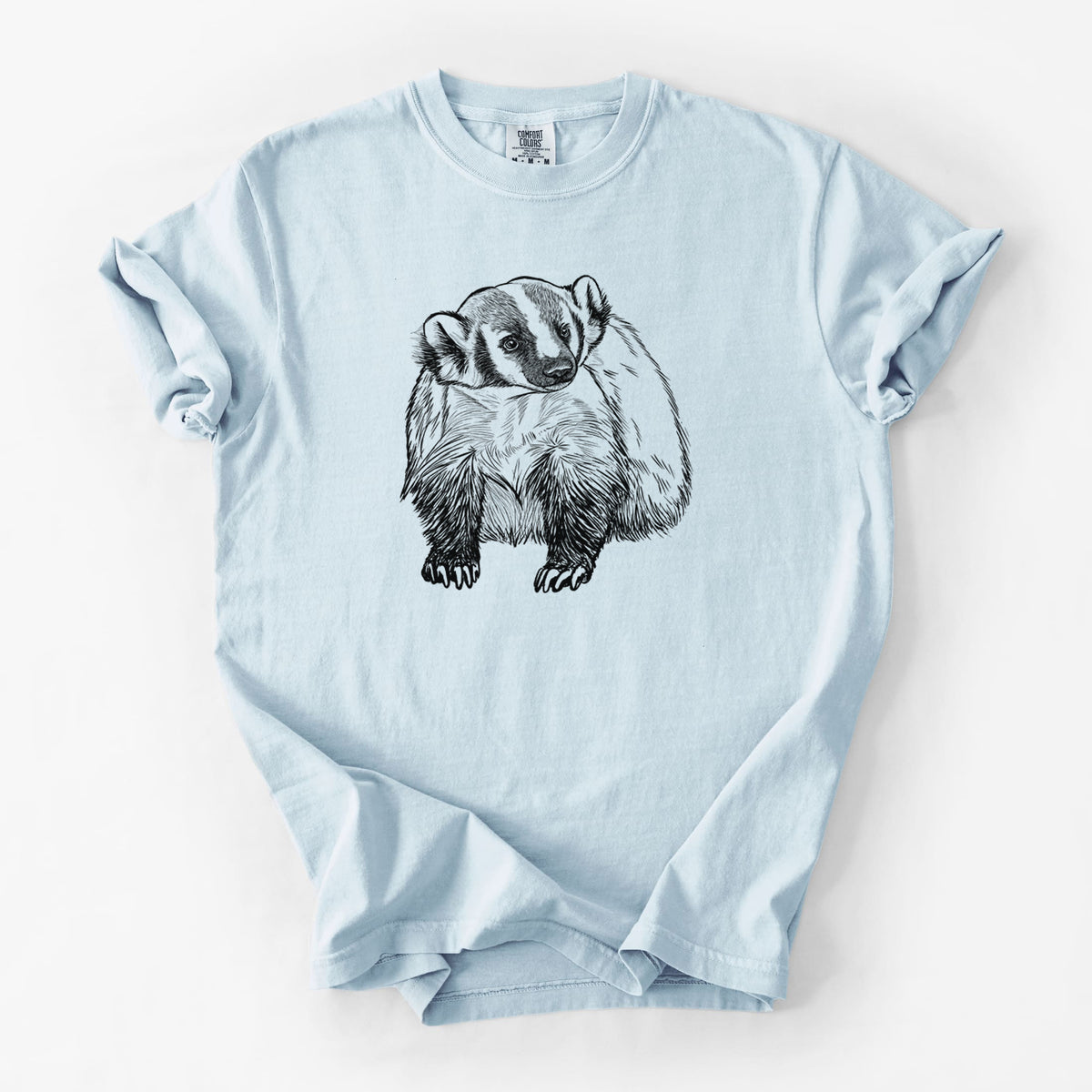 Chambray blue Comfort Colors t-shirt laid flat, printed with a detailed black ink illustration of an American badger facing forward.