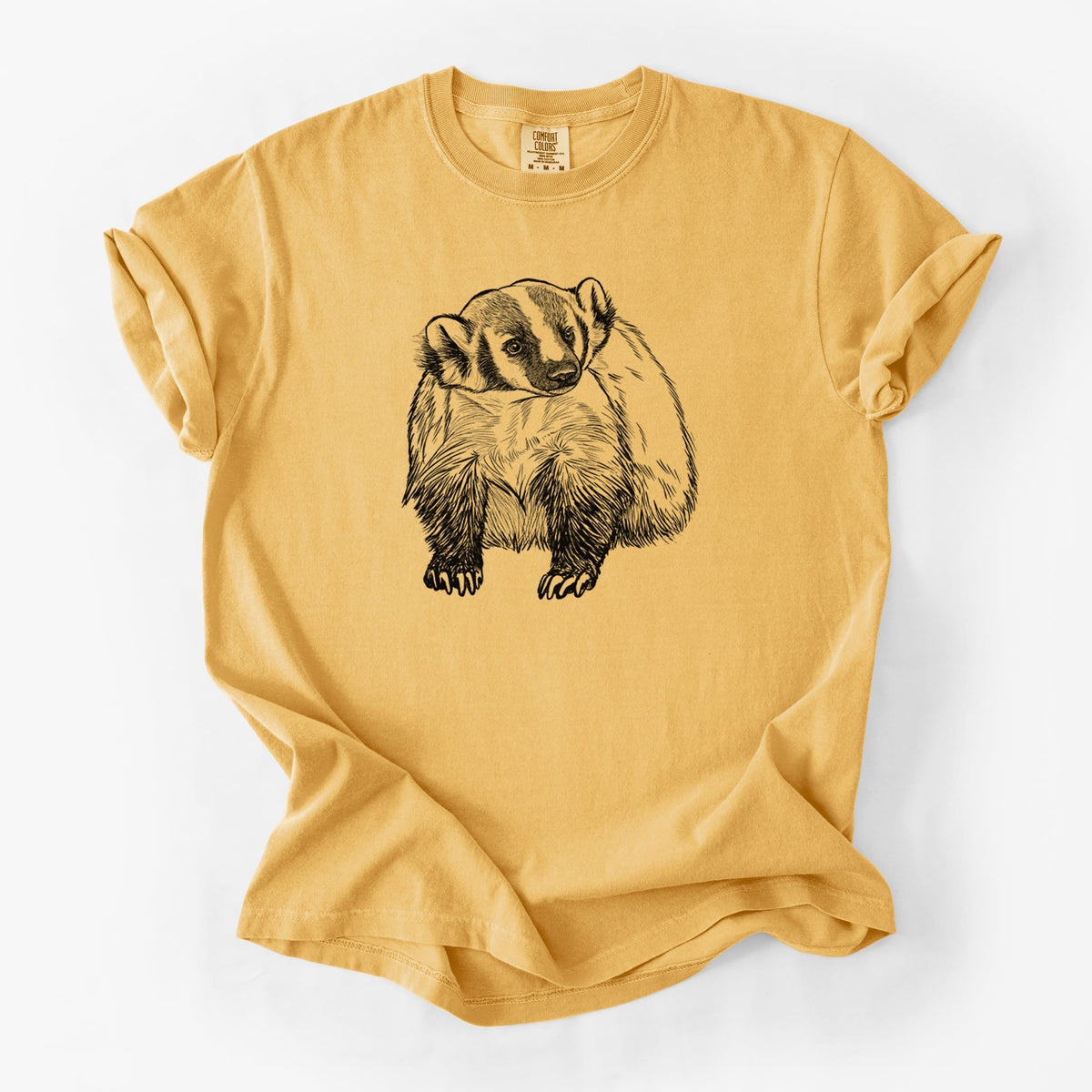 Golden wheat yellow Comfort Colors t-shirt laid flat, printed with a detailed black ink illustration of an American badger facing forward.