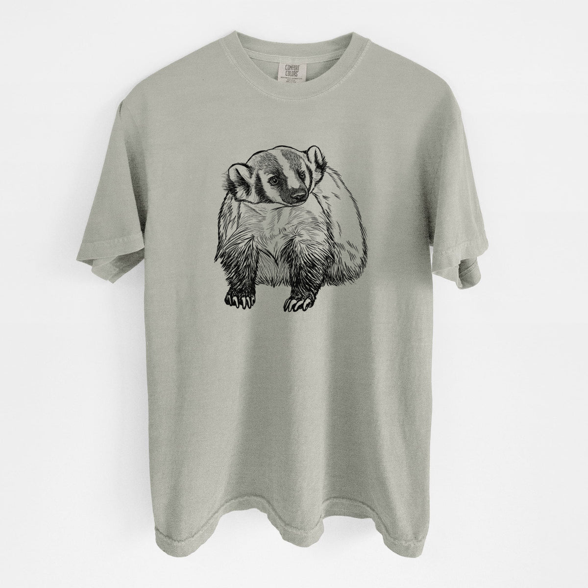 Sandstone beige Comfort Colors t-shirt laid flat, printed with a detailed black ink illustration of an American badger facing forward.